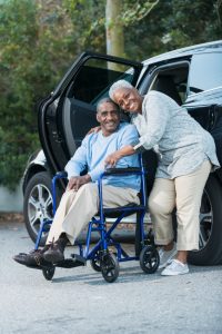 Senior couple with man in wheelchair next to car