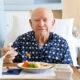 Senior male patient in hospital eating lunch